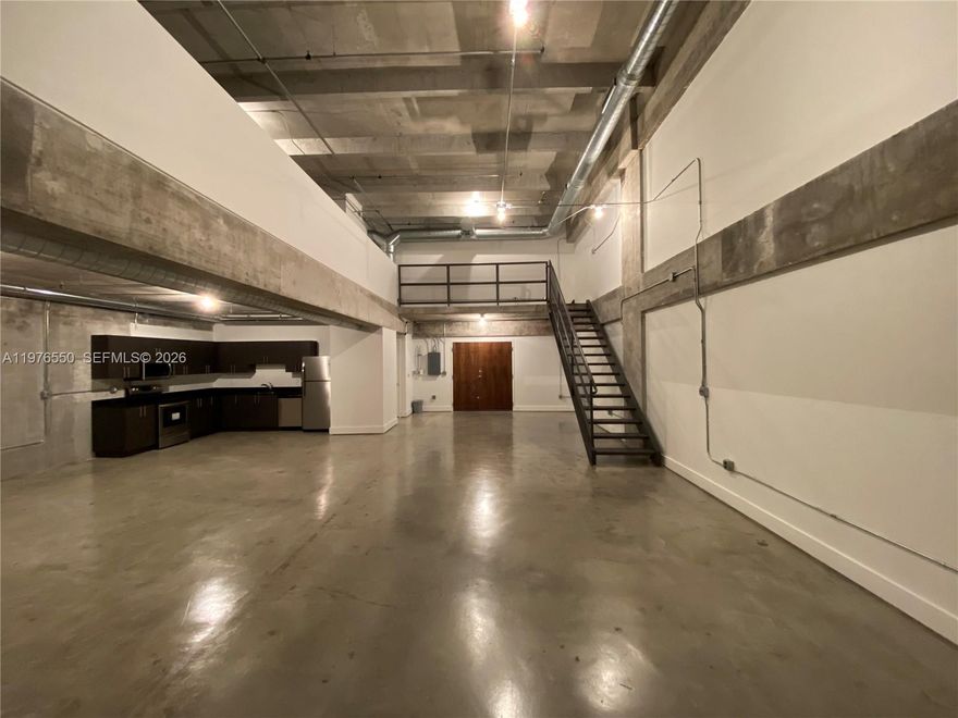 Experience true loft living in this stunning NY-style industrial residence featuring 20-foot ceilings and polished concrete floors throughout. The expansive open floor plan offers a bright and airy feel, highlighted by a lofted mezzanine with a spacious bedroom and full bathroom upstairs.

The main level includes a large full bathroom, in-unit stackable washer and dryer, and an open balcony with sweeping views of Wynwood and Midtown Edgewater. One covered parking space is included.