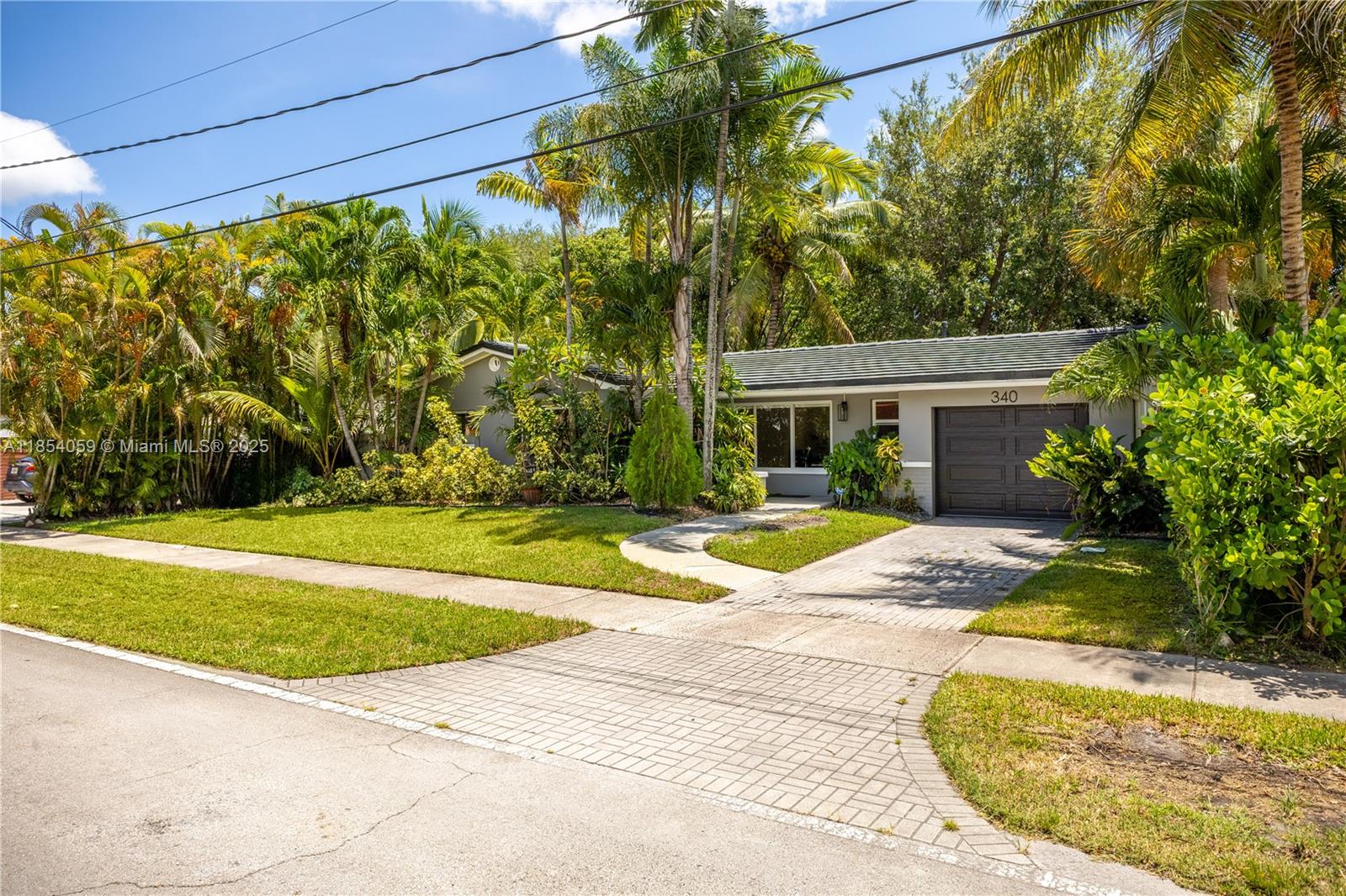 Mid-century design, original terrazzo floors, and an oversized 9,375 SF lot make this North Miami home stand out. The 3 BD, 2 BA layout features an updated kitchen with a gas stove and ample cabinet space, an open dining area, and a spacious living room filled with natural light. Impact windows throughout. One-car garage plus driveway parking. The fully fenced backyard is perfect for pets, kids, or weekend barbecues. Mature trees and tropical landscaping create a lush, private setting with plenty of space to relax and unwind. Dedicated laundry area with washer and dryer. On a quiet residential street near Whole Foods, Barry University, and local restaurants and shops. Just 15 min to the beach, Bal Harbour, Aventura, the Design District, and Wynwood, and 20 min to both MIA & FLL airports.