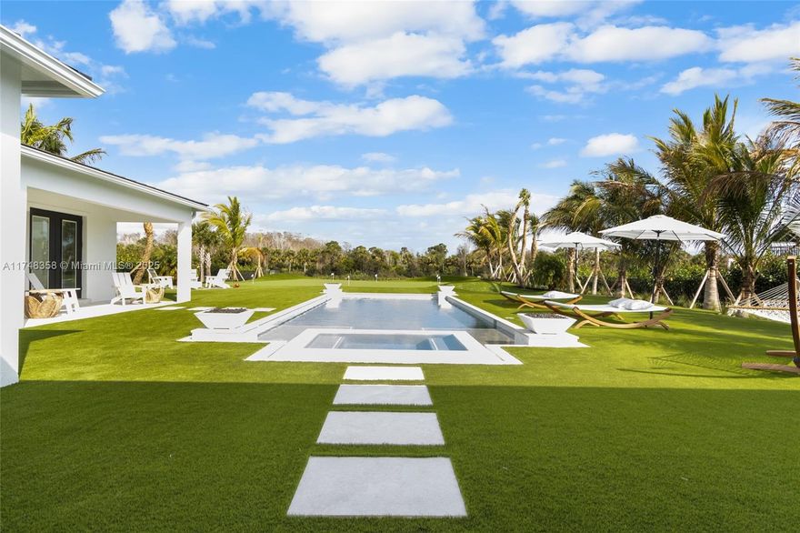 Interior designer custom finishes adorn this stunning 1 acre plus new estate home with a million dollar private backyard overlooking a lake and State Park. Amazing for living and entertaining guests with a significantly expanded driveway with plenty of parking, professional grade huge putting/chipping green with 2 Scottish-style revetted bunkers, a soccer/lacrosse practice field, custom summer kitchen overlooking a tranquil pool and spa, all framed by extensive tropical landscaping. Bonus features include a state of the art professionally installed movie theater. A serene guest/pool house is set up as a yoga/pilates studio. More possibilities remain for a private zen garden or a sports court. Gated community. Too many other features to mention... Come see it and make this home your own!