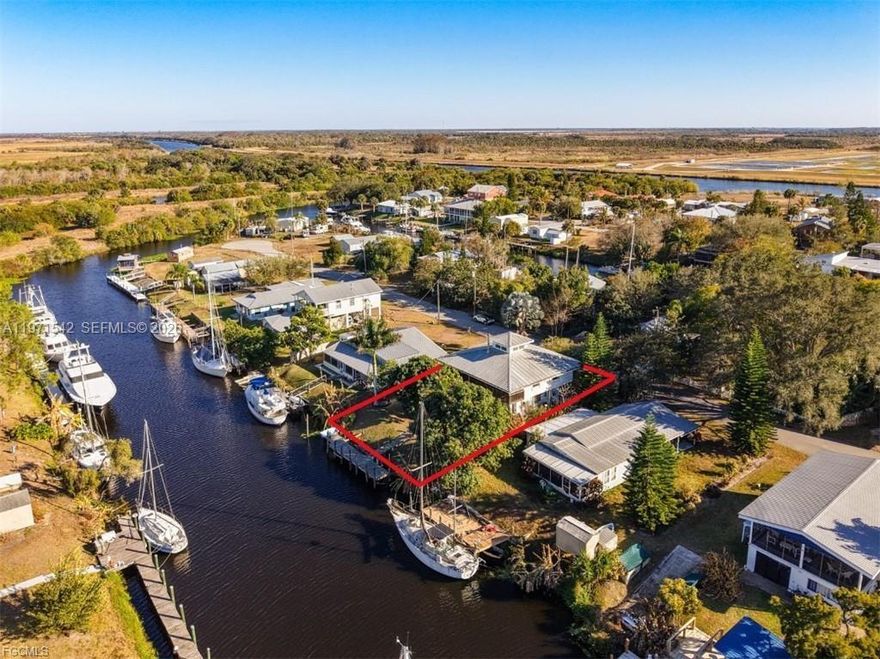 Waterfront Retreat in Turkey Creek – Gateway to Florida’s Legendary Waterways! Tucked away in the distinctive boating community of Turkey Creek, an Ortona subdivision adjacent to the historic Ortona Locks, offers an authentic Old Florida lifestyle with exceptional boating access. Set on a 65’ x 100’ deep-water canal lot, the property features a sturdy dock equipped with water and electric, providing effortless access to the Caloosahatchee River, part of the Intracoastal Waterway. The wood-frame home is elevated on a solid concrete block foundation with concrete pilings and topped with a durable metal galvalume roof. The upper level offers approximately 1,300+/- square feet, featuring two bedrooms, one bath, a galley kitchen, and a spacious great room for living and dining. The heart of the home is the dramatic living area, highlighted by a rustic tongue-and-groove vaulted wood ceiling, a cozy Franklin stove, and expansive sliding glass doors that open to a second-living-room-sized screened porch—perfect for relaxing while taking in tranquil canal and waterfront views. The lower level includes a garage, a workshop with built-in workbench and generous storage for projects, a laundry area, and a second full bath. Conveniently located just 15 minutes from downtown LaBelle and 20 minutes from downtown Moore Haven, this unique waterfront retreat truly delivers on the promise to slow down, simplify, and savor life on the water.