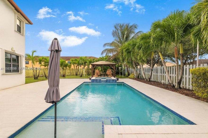 Discover the perfect blend of space, elegance, and resort-style living in this stunning two-story home set on an impressive 11,980 sq. ft. lot. Boasting a 3-car garage and an expansive driveway, this residence offers both comfort and convenience for families, entertainers, and those seeking elevated living. With 5 bedrooms (one bedroom downstairs), 4 bathrooms, and 4,320 sq. ft. of living area, there is truly room for everyone.Step inside to find a beautifully updated kitchen and two remodeled bathrooms, all completed in 2022 with modern finishes and thoughtful design. Wood stairs and contemporary light fixtures add a sophisticated touch, enhancing the home’s warm yet refined ambiance. The outdoor space is a true Florida oasis. Enjoy travertine flooring throughout the backyard, an aluminum terrace, and a charming wood gazebo perfect for gatherings. Relax in your private pool and Jacuzzi, equipped with colored lighting and a propane gas heater—ideal for evening dips or weekend fun. Additional upgrades include two water filtration systems, a sprinkler system, and accordion shutters throughout, ensuring comfort and peace of mind year-round. Located inside a secure gated community, residents enjoy top-tier amenities including a gym, playground, community pool, and splash water park—everything you need for a vibrant and active lifestyle. This exceptional property offers the perfect combination of luxury, functionality, and outdoor enjoyment.