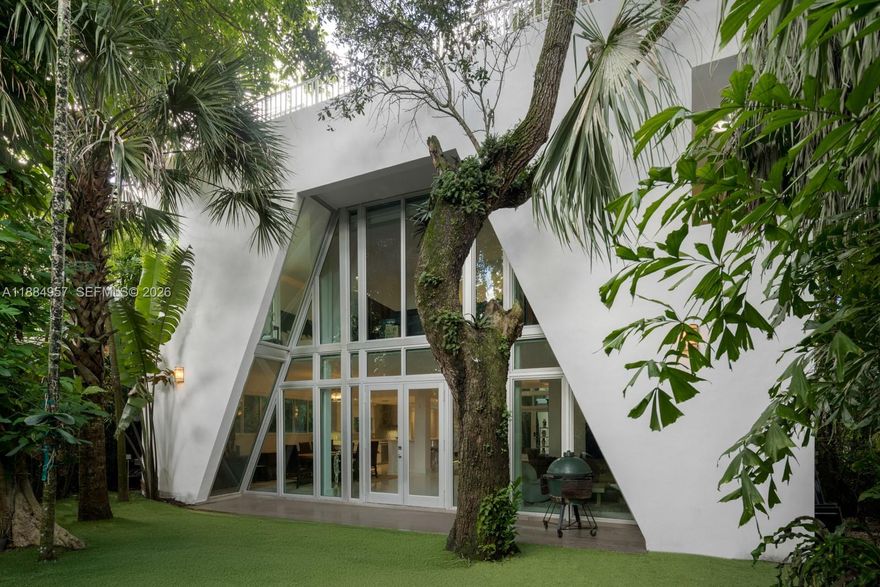Designed by architect D.B. Lewis, this gated 2017 contemporary home in Coconut Grove offers a spacious layout ideal for entertaining. A dramatic three-story atrium greets you on entry, anchored by two mature oak trees. The lower level features a seamless indoor-outdoor flow and a chef’s kitchen with a gas Gaggenau cooktop and Miele and Viking appliances. Five en-suite bedrooms include a private primary wing with lounge, spa-style bath, and windowed walk-in closet. A 1-car air-conditioned garage and driveway space for three more vehicles add convenience. The rooftop retreat boasts a pool, gazebo, and cabana bath.