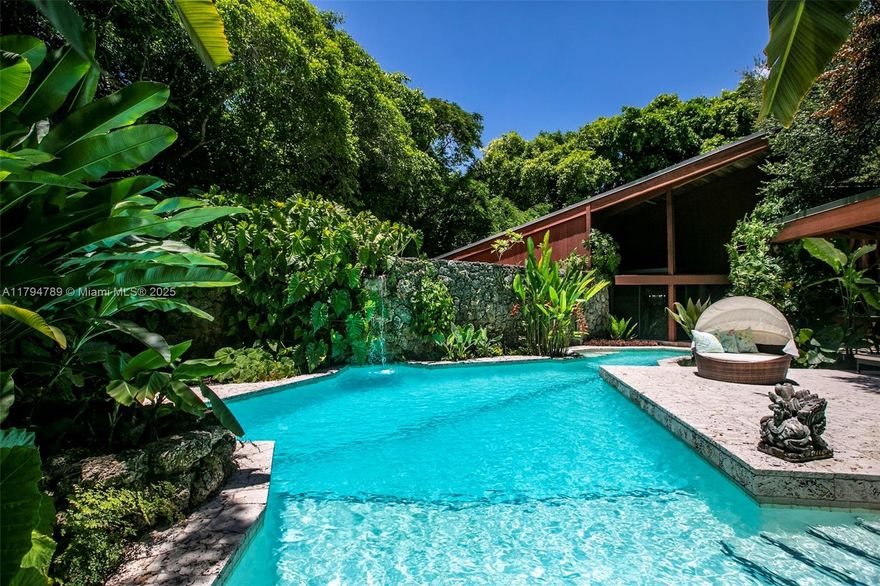 Designed by renowned Miami architect Chayo Frank as his personal home, this one-of-a-kind residence is nestled in the heart of Ponce Davis, embracing its lush South Florida setting. Built with a commercial structural steel frame encased in California Redwood, the 5,128 sq ft home features a vast living room with walls of glass overlooking a tropical garden. Inspired by the organic style of Frank Lloyd Wright, it includes a freeform pool with a 50’ lap lane, coral rock grottos, winding paths, multiple terraces, a dramatic double-height primary, a guest suite and a treehouse-style office accessed by ladder. A true architectural treasure, this home offers privacy, character, and a seamless connection to nature, an extraordinary retreat in one of Miami’s most coveted neighborhoods.