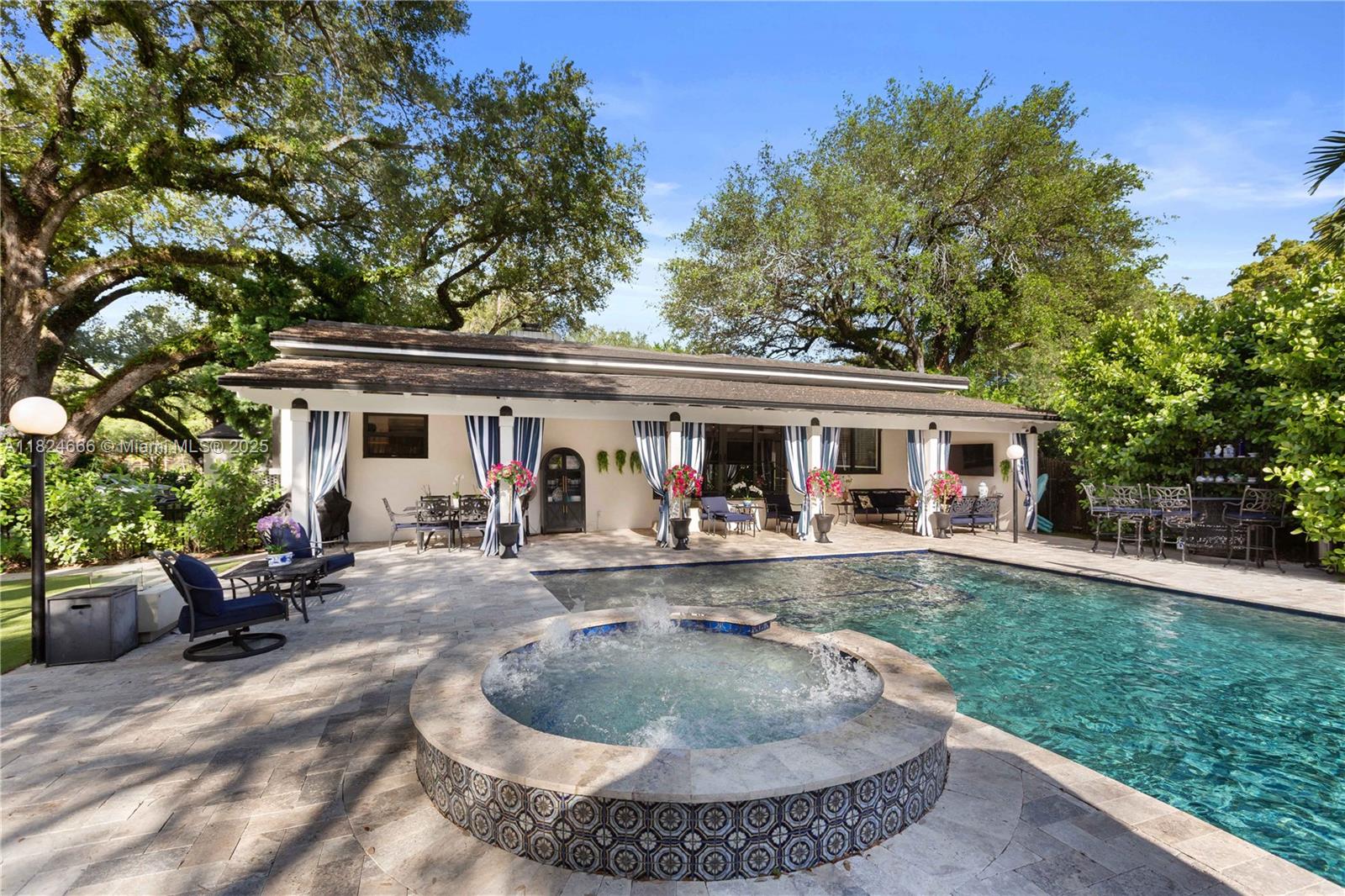 This is your chance to own and live in a Coral Gables legacy home. Nestled on almost half an acre with majestic mature oak trees, this fully renovated home features high ceilings and hardwood floors throughout. The kitchen offers high-end stainless steel appliances, a 6-burner gas stove, and natural stone tops and backsplash. The 4-bedroom/3-bath + den main house is complemented by a 1-bedroom/1-bath in-law quarters with private entrance and walkway access to parking. The primary bedroom opens to a second private patio and garden. Enjoy a heated Diamond Brite pool, hot tub, covered terrace, new AstroTurf, and Sonos outdoor speakers. All plumbing, electrical, roof, impact windows, and doors are new. Two-car garage and plenty of parking. Don’t miss this rare opportunity!