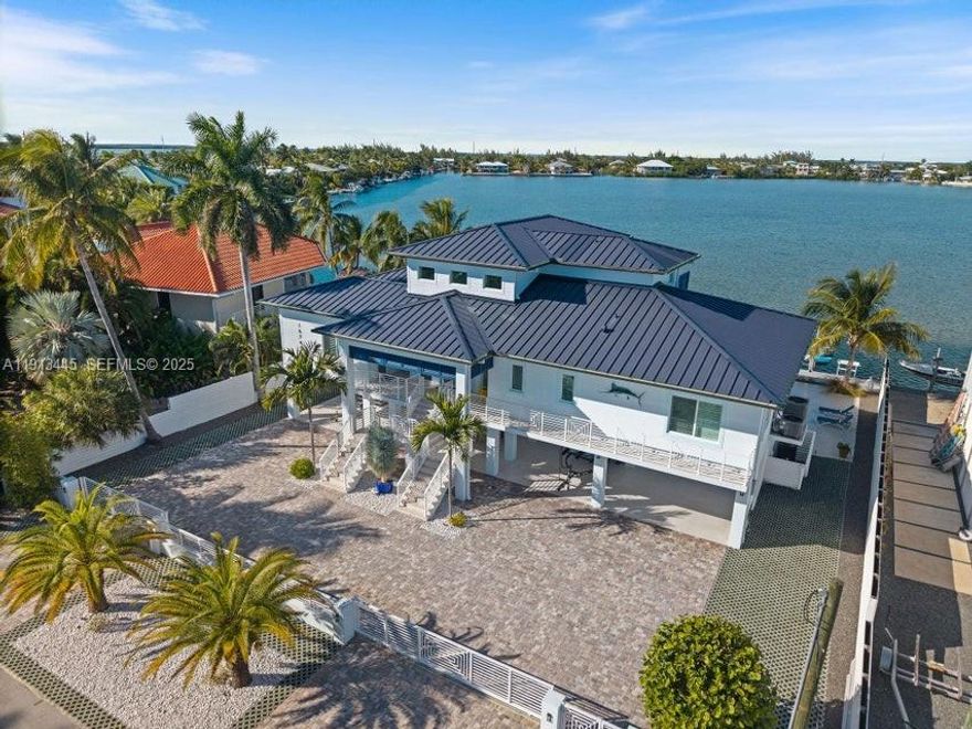 Step into your own exquisite waterfront sanctuary, Casa Del Mar, in Sugarloaf Shores is where clean, modern design meets relaxed Florida Keys ease. This beautifully built CBS home with impact windows and doors delivers 4 spacious bedrooms and 4.5 baths, wrapped in contemporary style and coastal charm.
Inside, the heartbeat of the home is a true chef's kitchen featuring high-end appliances, huge quartz waterfall island, and an open-concept design that flows into bright living and dining spaces. Oversized terraces extend your outdoor living space, complete with a summer kitchen made for alfresco cooking under sunlit skies and moonlit nights. The primary suite is its own private retreat, an entire level devoted just to you. Enjoy a sun-washed deck, generous walk-in closet, and a balcony that frames shimmering water views. It's a Zen-zone where you can start and end the day in absolute calm.
Boaters will love the serious waterfront access: a 100-ft seawall, a 25K lb boat lift, plus a floating dock/jet ski platform. From here, your days can go in any direction: fishing, sandbars, or just a quick ride out to open water. Outside, the heated pool and masterfully designed lounging and cooking areas create an effortless indoor-outdoor lifestyle. Just 20 minutes from Key West. This home strikes the perfect balance between turnkey serenity and easy access to everything that makes the Florida Keys so remarkable. Casa Del Mar is your luxury waterfront escape, ready to enjoy from day one.