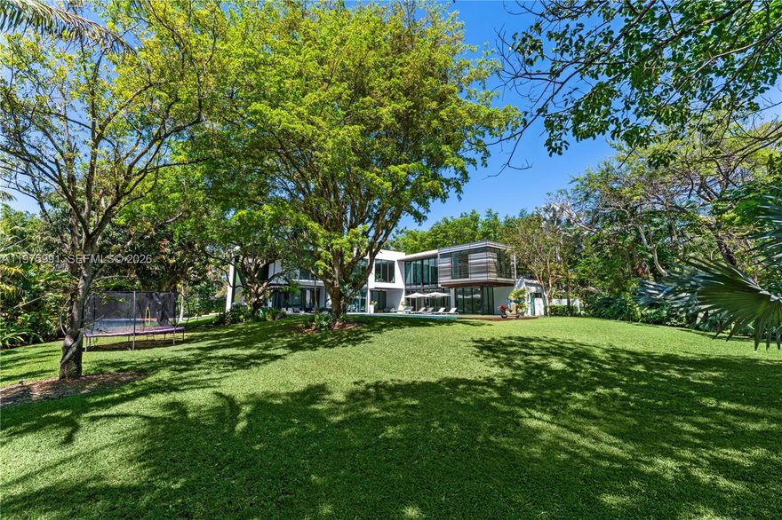 Completed in 2019 by Norway Builders, this exceptional residence sits on a coral ridge along a quiet, tree-lined street on a lush acre lot. Soaring 25+ ft ceilings and expansive open living areas are filled with natural light and overlook a professionally landscaped, resort-style backyard with sparkling pool. Upstairs offers 5 bedrooms, 4 baths, and a family room; the main level includes a VIP guest suite and staff quarters. High-end finishes feature an Italian kitchen and closets, Miele appliances, Spanish stone, oak floors, glass railings, and a dramatic pivot entry door. Per appraisal: 6,267 LA, 7,095 adjusted, 8,989 total. Includes 16kW solar and Tesla battery backup.