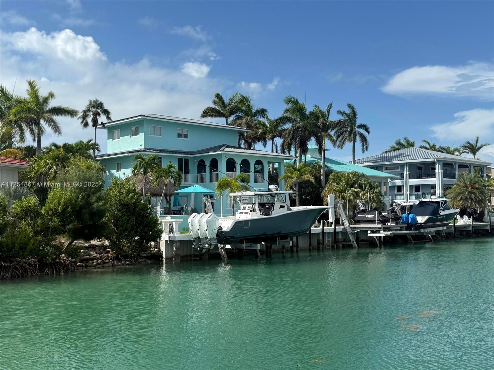 28-day minimum rental. Welcome to paradise! This luxury 4,700+ SF custom home is just 1,100 ft from the ocean inlet with no fixed bridges, 100' wide canal, and ocean views from the 3rd-story loft. Includes two 25K lb boat lifts (up to 40' boats), double jet ski lift, paddle boards, fishing rods, golf carts, and more. Kid-friendly with 6 bunk beds—sleeps 16+. Features hurricane impact windows, custom wood floors, new appliances & HVAC, 24' ceilings, screened lanai, heated/chilled pool & spa, tiki hut with full outdoor kitchen. Fully furnished and first time on seasonal rental market. EV charger onsite. Extra lot for parking. Walk or golf cart to top restaurants. Available: Sept–Nov 2025, Feb & May 2026. Rates vary by month.