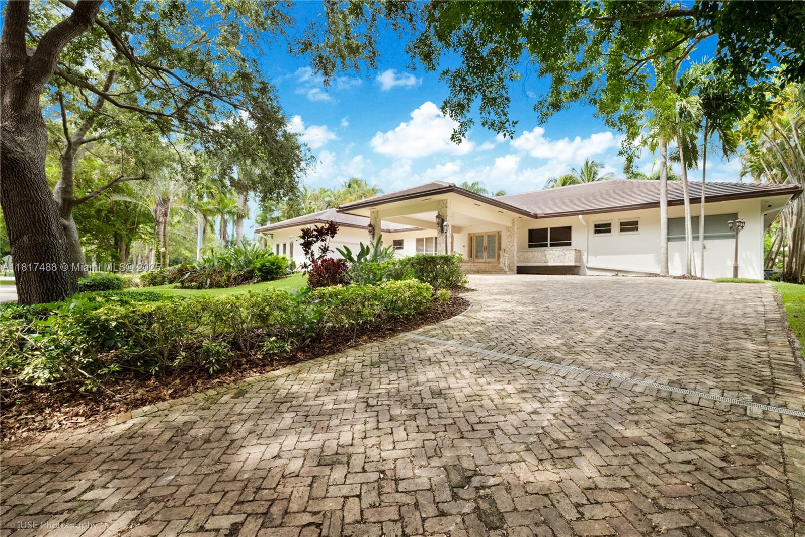 Enjoy the lifestyle and amenities of the Islands of Cocoplum in this refreshed one-story residence, ideally located on a quiet, low-traffic cul-de-sac. A wide driveway and porte-cochere lead to double doors opening to a foyer, elegant living room with fireplace, and formal dining room that flows to a spacious covered terrace. Features include a family room, library/office with built-ins and bar, and a large kitchen with center island, gas range, electric oven, microwave, and breakfast area. The private bedroom wing offers four en-suite bedrooms, including a generous primary suite with sitting area, whirlpool tub, and steam shower. Staff room, two-car garage, and basement storage complete the home.