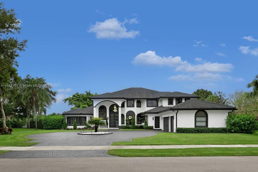 In Davie, this sprawling 7-bedroom, 4.5-bathroom estate spans 6,000+ sq. ft. with lake views, a newly remodeled saltwater pool, and outdoor kitchen. Features include high ceilings, white porcelain tile, and wood flooring on the second level. The home’s two kitchens are equipped with new appliances, while the first-floor master suite includes its own A/C and water heater. Enjoy a 10-seat theater room, generator, impact windows, and plantation shutters. Outdoors, a basketball court and mosquito system enhance the builder’s acre, perfect for luxurious entertaining and family living.