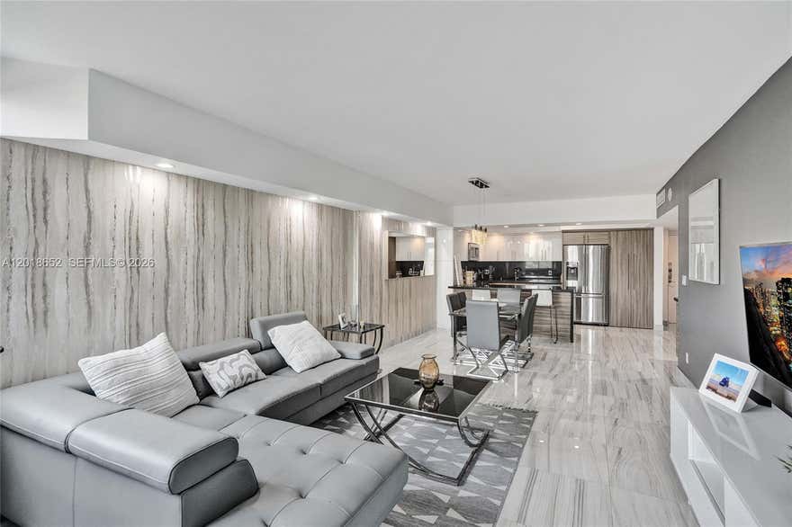 One of Sunny Isles Beach's most flexible-rental properties — own a 2BR + den / 2BA residence in a building that permits daily, weekly, and monthly rentals. Rare zoning on this stretch of Collins Avenue. This renovated unit features a modern open layout with light wood-look flooring, a stainless steel appliance package, stone countertops, and updated bathrooms with contemporary finishes. The den functions as a flexible third sleeping space, home office, or media room. Private balcony with glass railings offers elevated views of Sunny Isles and the surrounding skyline. Steps from the Atlantic Ocean across Collins Avenue, and minutes from Bal Harbour Shops, Aventura Mall, and Miami's premier dining and nightlife. Building amenities include heated pool, tennis courts, fitness center, mini market, cafeteria, game room, on-site laundry, and 24-hour concierge. HOA covers high-speed internet, cable, and central A/C — keeping ownership costs predictable and rental margins strong. Whether you're scaling a short-term rental portfolio via Airbnb or VRBO, securing a personal beach getaway, or holding for long-term appreciation, this is one of the most versatile ownership opportunities on Collins Avenue.