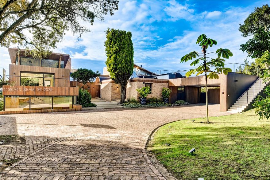 Set on an expansive approximately 3.68-acre lot (14,900 m²) with nearly 9,700 square feet (900 m²) of thoughtfully designed living space, this architectural residence is a masterclass in refined indoor-outdoor living. Warm, sophisticated finishes are complemented by floor-to-ceiling German thermo-acoustic windows that flood the interiors with natural light while seamlessly framing the surrounding landscape. Radiant floor heating and curated Delta Light illumination enhance both comfort and ambiance, while the home’s expansive social areas unfold effortlessly onto multiple terraces with captivating views, each anchored by fireplaces. 

A dramatic double-height hall introduces a private bedroom wing featuring four well-appointed bedrooms, including a serene primary suite with a spa-inspired bath and its own BBQ terrace. Designed for both relaxation and entertaining, the residence offers a collection of exceptional amenities, including a jacuzzi, gym, study, game room, and extensive outdoor living spaces. Additional features include security quarters, a large laundry area, generous storage, and full backup power, along with three covered parking spaces and ten exterior, delivering an unrivaled combination of scale, privacy, and elevated design.