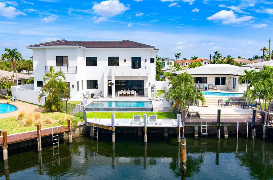 Introducing a breathtaking contemporary luxury home, ideally situated on the deep waterfront (30 ft) of the sought-after "Lake Placid". This impeccably designed residence boasts an open & modern floor plan, professionally furnished & decorated to perfection, creating an ideal space for entertainment & relaxation. With 4 stunning en-suite rooms, including 2 master bedrooms (1 downstairs), high ceilings, & impact windows, every detail exudes luxury and comfort. Natural light showcases the top-of-the-line finishes & appliances. Beautiful cabinetry, porcelain, wood floors & Sonos music system add to the allure of this elegant home. Enjoy awe-inspiring water views & experience a lifestyle of convenience & ease (park & Tennis Center just steps away), and the beach just a short ten-minute drive.