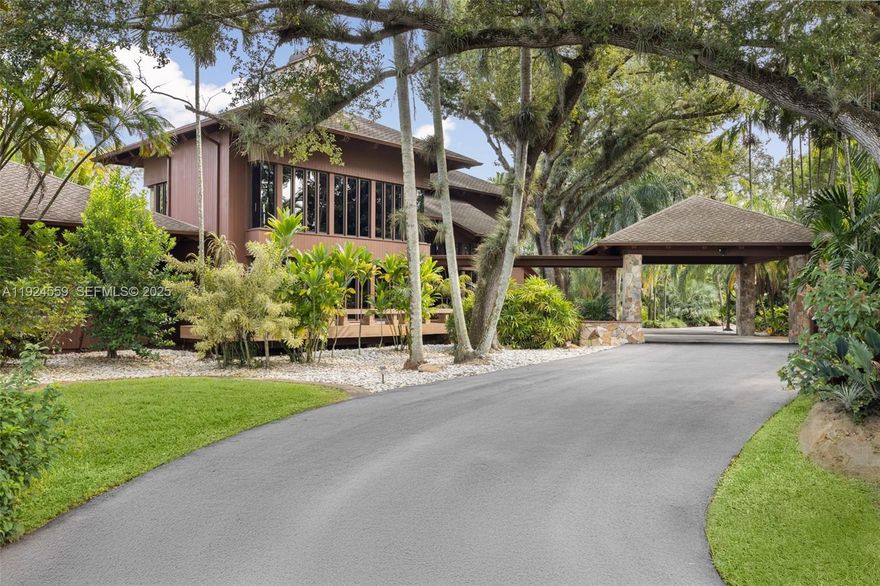 Rare 1980 architectural masterpiece by renowned architect John Weller, whose organic design philosophy created a home that becomes part of the land. This 3 bd + loft, 3.5 ba, 4,318 SF custom home on 4+ acres shows his vision with over 100 impact windows and sliders that frame serene views and dissolve boundaries between indoors and out. 

You are welcomed by an artistic Italian copper security door beneath the porte-cochere with a circular drive. Natural materials flow throughout, including dark wood and stone tile in each living space, Honduran mahogany cabinetry and granite counters in the kitchen, exposed tongue-and-groove beams, and a dramatic double-sided river rock fireplace rising through the loft. The interior and exterior blend seamlessly with two connecting terraces on each level spanning the rear of the home, private terraces off each room, a uniquely shaped pool extending beneath an overpass to an elevated BBQ area, and meandering rock pathways through lush landscaping of mature oaks, palms, bamboo and fruit trees. The property also features a 2,000 SF workshop with electricity, a 4 car detached garage, home generator and mixed-use residential/agricultural zoning. 

The home is move-in ready, well maintained and the grounds have been meticulously restored. For discerning buyers who appreciate organic architectural style and craftsmanship, this is a livable work of art where Weller's integration of natural elements creates a tropical South Florida sanctuary.