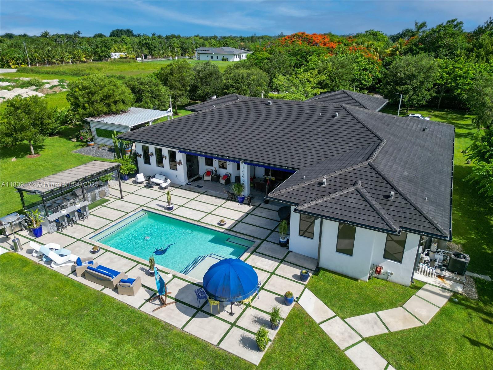 Experience luxury living in this stunning custom-built modern estate nestled in the heart of the Redlands. This 5 bed, 4 bath masterpiece sits on over 54,000 sq ft of lush, tranquil land at the end of a private cul-de-sac. Enter through a gated entrance to a grand front driveway, 2-car garage, and 2 covered carports. Inside, soaring ceilings, impact doors/windows, and sleek finishes define the space. Enjoy a sparkling pool, a gas-powered generator with 3-week capacity, and an EV charger. The property features two A/C-equipped sheds and an abundance of mature fruit trees, offering the perfect blend of comfort, style, and self-sufficiency with your own private water wells.