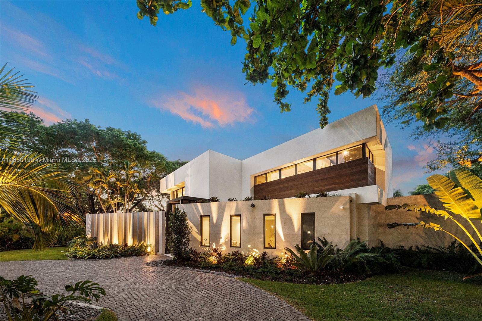 This luxurious 5-bedroom, 6-bath Florida Modern residence boasts over 5,500 square feet of elegantly designed indoor and outdoor living space, nestled among lush tropical landscaping for ultimate privacy and tranquility.
Floor-to-ceiling windows bathe the interiors in natural light, highlighting an open-concept layout that effortlessly blends indoor sophistication with outdoor serenity—ideal for entertaining. A dramatic dining area with soaring 22-foot ceilings and a striking floating staircase sets the tone for the home’s impressive design.
The impeccably curated Armazem kitchen—with a custom wine cellar—flows into a spacious great room that opens to a covered poolside terrace featuring a fully equipped outdoor kitchen with an icemaker.
