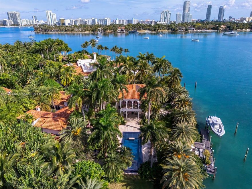 This Mediterranean Revival estate seamlessly blends classic architecture with modern luxury. Fully renovated in 2009, the home sits on a sprawling 35,348 sq. ft. lot on prestigious Palm Island, offering 220’ of prime south-facing waterfront capable of accommodating yachts up to 205’. A spacious addition includes a luxurious primary suite, chef’s kitchen, and family wing. Exceptional amenities include a home theater, gym, steam rooms, bocce court, wine cellar, heated pool, spa, private beach, and a serene courtyard. A separate guest house, smart home technology, lighting controls, and solar panels complete this lush, gated haven. Surrounded by exotic landscaping, this estate embodies sophistication and privacy in the exclusive, police-guarded Palm Island community.