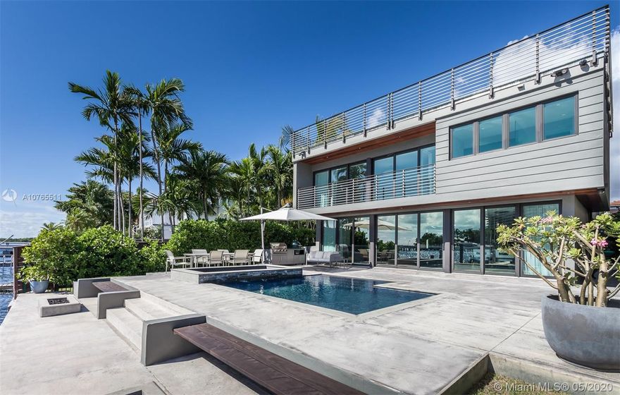 This custom waterfront home in Coconut Grove, with five bedrooms, five baths, one half bath, LA 5,035 sq ft, and 7,371 Total square footage, is a warm contemporary delight great for entertaining. Its wonderful open spaces, flexible floorplan and sun-filled impact windows and doors are complemented by panoramic water views. The property includes a 50-foot dock with two heavy-duty boat lifts, and deep navigable water with no bridges to bay make it a boater's dream. A beautiful third floor terrace, perfect for entertaining alfresco, is reached by an impressive wood spiral staircase. The home also features an onyx-bottom heated pool and spa, fiber optic home connectivity, and a whole house generator with 1,000 gallon propane tank.
