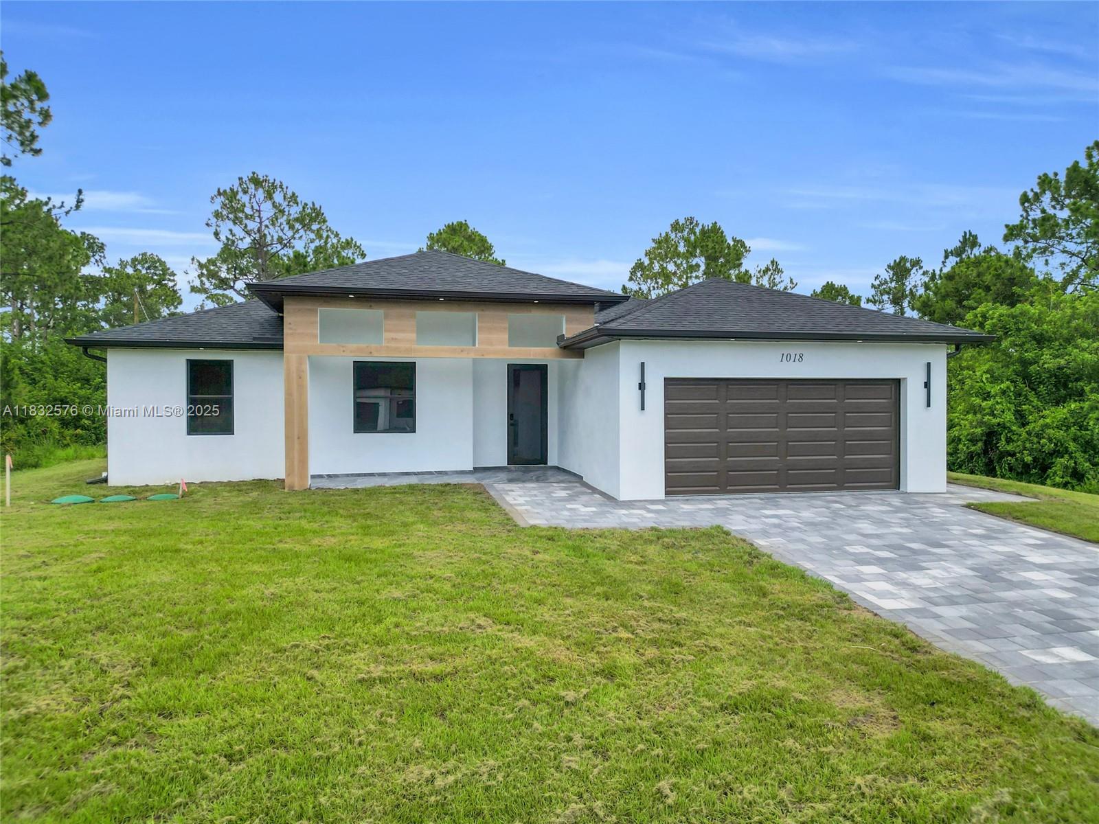 New construction at 1018 Calvin Ave, Lehigh Acres: 4 beds, 3 baths on a half-acre lot. Open-concept layout with abundant natural light and tile flooring. Kitchen boasts shaker-style wood cabinets, center island, and premium finishes flowing into the living and dining areas. Master suite offers a walk-in closet and en-suite bath with dual sinks and modern fixtures. Three additional bedrooms share a stylish full bath. Enjoy an indoor laundry room, 2-car garage, and impact windows/doors. Generous lot with paved driveway provides outdoor living and gardening potential. Located in a quiet, non-HOA neighborhood close to schools, shopping, and major roads—move-in ready for Southwest Florida living.