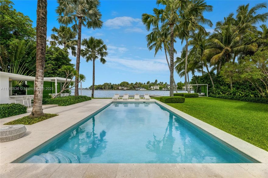 Step into this breathtaking waterfront sanctuary on prestigious North Bay Road. This 4-bedroom, 4.5-bath mid-century estate sits on an oversized 27,013 SF lot w/ 113’ of pristine bay frontage. A grand koi pond entrance leads to sunlit interiors, featuring L-shaped living room, bar, private office, media room, & formal dining area. The fully renovated Bulthaup kitchen combines style & function w/ high-end appliances & a second prep kitchen. The primary suite mesmerizes w/ sweeping water views, dual walk-in closets & a luxurious spa bath. Outdoors complete w/ lush landscaping designed by Raymond Jungles, heated pool, dining & seating pavilions, private dock & a Kalamazoo built-in summer kitchen w/ pizza oven. This home blends privacy & serenity, moments from Miami Beach’s vibrant lifestyle.
