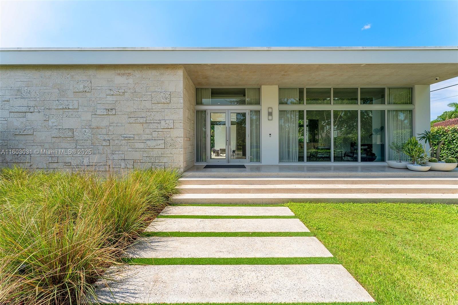 This 1-story contemporary custom home welcomes you w/ a gated entrance and an Oolite stone wall, ensuring privacy & security on a beautifully landscaped green lot. Step inside to discover high ceilings & abundant natural sunlight streaming through high-impact windows. The interior features polished concrete & hardwood floors throughout. The home includes 3 bed rms with ensuites, & an additional bed rm converted into an office/den. The primary suite ft. a spacious layout, a walk-in closet, & a spa-like bath rm w/ a soaking tub, a glass-enclosed shower, & dual vanity. The open kitchen boasts solid wood cabinetry, Gaggenau & Bosch appliances, & a marble waterfall kitchen island that opens to the family rm, offering tropical oasis views of the oversized pool, patio, & lush greenery.