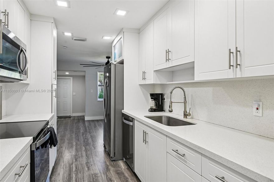 This home blends modern style with everyday comfort. Featuring a new 2023 roof, tankless water heater, impact windows and hurricane-rated doors for peace of mind. Modern laminated wood flooring and baseboards, complemented by a 2020 AC system. Enjoy the updated kitchen with gleaming quartz countertops and sleek stainless steel appliances. Both bathrooms offer refined finishes & fixtures. Den/office room with closet acts as an additional room for more space. Outside, the large yard has space for a boat or RV, a driveway for multiple cars. Abundant natural light, enhanced by recessed lighting creating a clean, open feel. Located just 2 minutes from the beach, shopping, dining, and major routes, this home offers a perfect balance of style and location. No HOA!