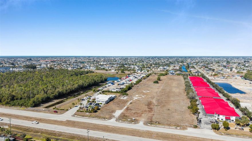 Why wait to develop when you can own an income-producing asset with exceptional future potential? Rare investment opportunity offering approximately 5.87 acres along highly traveled SW Pine Island Road in Cape Coral. Currently operating as a cash-flowing outdoor storage facility with approximately 185+ parking spaces, this unique property also includes a large repair shop featuring 2 oversized 18’ overhead bays, 4 additional bays, and office space. Utilized for boat and auto repair, the property offers excellent flexibility for a variety of commercial uses. The site is fully fenced with keypad entry and security cameras, providing secure access for tenants and operations. Approved city plans allow for expansion of the storage area, including a detention pond and fire hydrant access. Total acreage includes an additional 1.02-acre parcel on the north end facing Ceitus Parkway, included in the approved site plan. Improvements include a 6,000 sq ft shop building. Prime location near major retailers and national brands, including the -anchored Coral Shores Shopping Plaza with, and nearby. Outstanding visibility, strong traffic counts, and future growth potential make this a premier commercial investment opportunity.