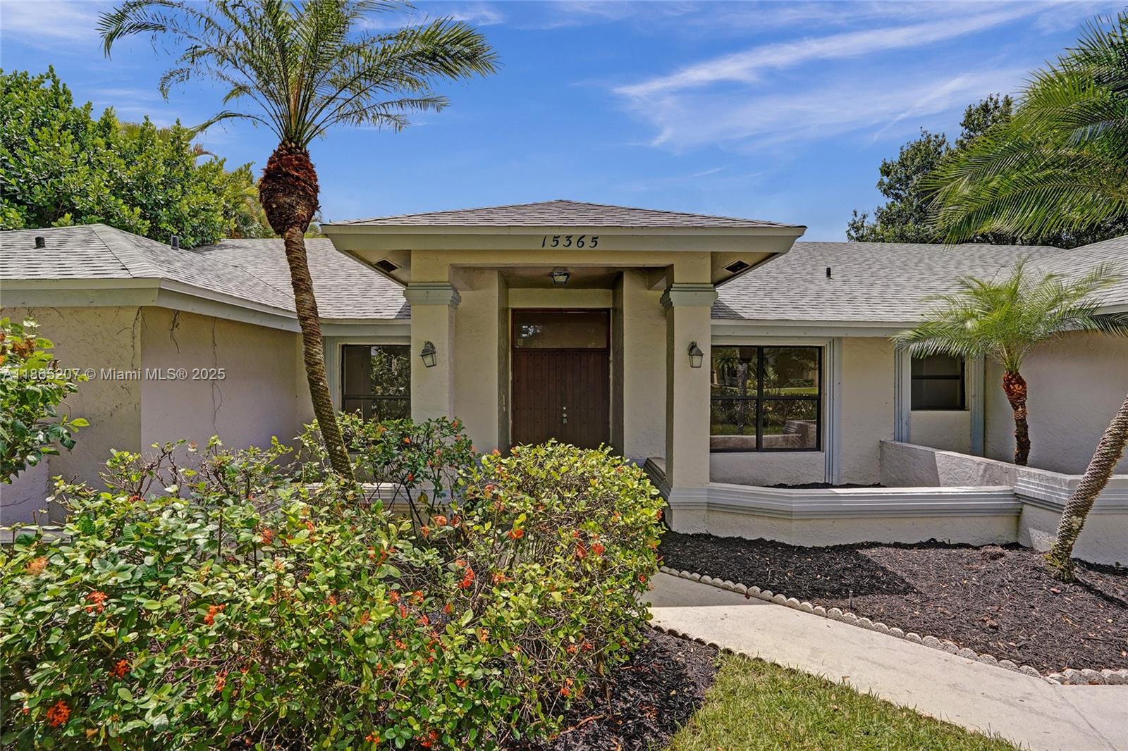 A rare opportunity to own a tropical half-acre estate in the coveted Meadow Wood neighborhood! This 4BD/2.5BA residence features a brand-new roof (2025), soaring ceilings, expansive windows, and a striking coral stone fireplace that elevates the open living spaces. Outdoors, enjoy a sparkling pool and covered patio surrounded by lush landscaping, ideal for both entertaining and relaxation. Two bedrooms were converted into a private apartment with its own kitchen and entrance, perfect for multi-generational living, guests, or added income, and can easily be restored. Zoned for Wellington’s top-rated schools: Binks Forest Elementary, Wellington Landings Middle and Wellington High School.