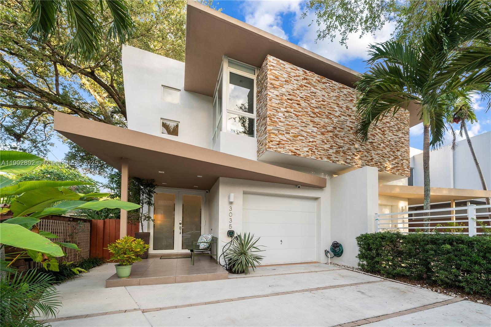 Architecturally striking 3BR/4BA modern home in the heart of Center Coconut Grove! Dramatic ceilings create a grand entrance with sweeping views to the tropical outdoors and waterfall pool. Light-filled interiors feature a sleek open-concept design. The contemporary kitchen showcases stainless steel appliances and a spacious island with Gas cooktop. Upstairs offers 3 ensuite bedrooms, including a primary suite with large walk-in closet and spa-inspired bath with rain shower, soaking tub, and dual vanities. Enjoy a private rooftop terrace with retractable awning. Additional features include EV charger, wiring for security cameras, gas dryer hookup, gated entry, and 1-car garage. Located just blocks from Coconut Grove Shops, Dining, Parks, and Biscayne Bay.