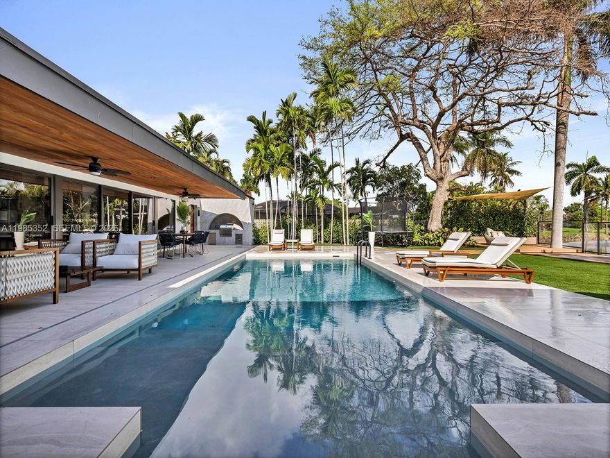 Fully reimagined modern residence built by the principal of META Development on a rare canal-front lot in prime N. Palmetto Bay, minutes from Pinecrest. Set on 14,947 SF with serene waterway views, this 4-bed, 3.5-bath home spans 4,323 SF adjusted area and was completely transformed in 2025 with designer-level finishes. The open-concept layout is bathed in natural light with a floating staircase, skylights, custom millwork, and designer LED lighting. The chef's kitchen features custom cabinetry, a book-matched porcelain waterfall island, Samsung appliances, wine and beverage refrigerators, and Hansgrohe fixtures. The primary suite offers a spa-inspired bath with soaking tub and an oversized, fully built-out walk-in closet. Custom built-ins extend through the kitchen, pantry, bar, closets, and baths delivering both function and artistry. A metal roof, new electrical panel, AV system, and two EV charging outlets complete the package. Outside, a covered wood-ceiling loggia opens to a heated pool and lush lawn along the canal, framed by palms and a clear fence; a true private oasis. Near top-rated schools, parks, and the best of Palmetto Bay and Pinecrest.