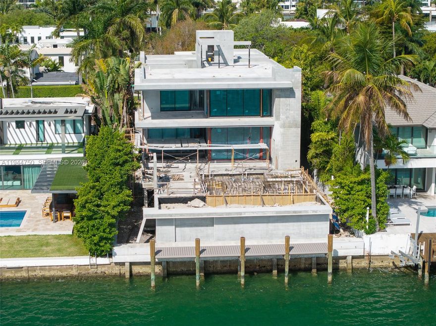 Luxury waterfront home being built with dramatic evening views of the Miami Beach skyline. Designed by Praxis Architecture, this 5 bed 5 and 1/2 bath home has 5,400 sq foot of living space under AC, with an additional 2,600 sq foot of understory with 9 foot height clearance for parking 5 cars, gym, storage area, games. Open floor plan with sliding telescopic doors for effortless indoor-outdoor living. Expansive primary suite includes a private covered patio. Featuring exquisite French oak flooring, marble bathrooms, this home offers a refined blend of elegance and functionality. The property boasts a covered summer kitchen, pool, dock with lift, and a rooftop terrace providing uninterrupted 360-degree views. Completion expected winter 2026.