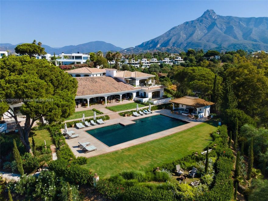 Property is located in Marbella, Spain. Beachcomber: Art, architecture, and engineering unite in this grand Spanish estate on the Golden Mile. With panoramic views of the Mediterranean Sea and Sierra Blanca mountains, this 9-bedroom villa boasts bespoke finishes and eclectic interiors by Luisa Olazábal. A grand salon, gourmet kitchen, and outdoor patio offer luxurious living. The lower level features an entertainment oasis with a movie theatre, spa, gym, and more. Outside, enjoy Andalusian architecture, lush gardens, a swimming pool, and paddle court. The master suite dazzles with wooden accents, a copper clawfoot tub, and private terrace. The guest house adds 7 bedrooms. Beachcomber is a timeless masterpiece, epitomizing luxury living in Marbella.