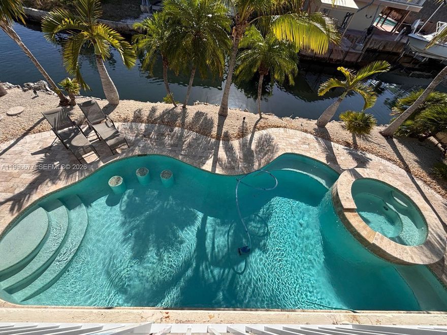 Premium Waterfront Oceanside home in Key Largo, Florida on a point lot on a main canal featuring water frontage on two sides with 180-degree water views, deep-water docking with 80 feet of dock space, a 15,000 pound boat lift & a cut in slip for your boat just minutes from the open ocean with a beautiful underground pool and hot tub and tiki hut. This tropical paradise sits on the end of a private street on a cul-de-sac.