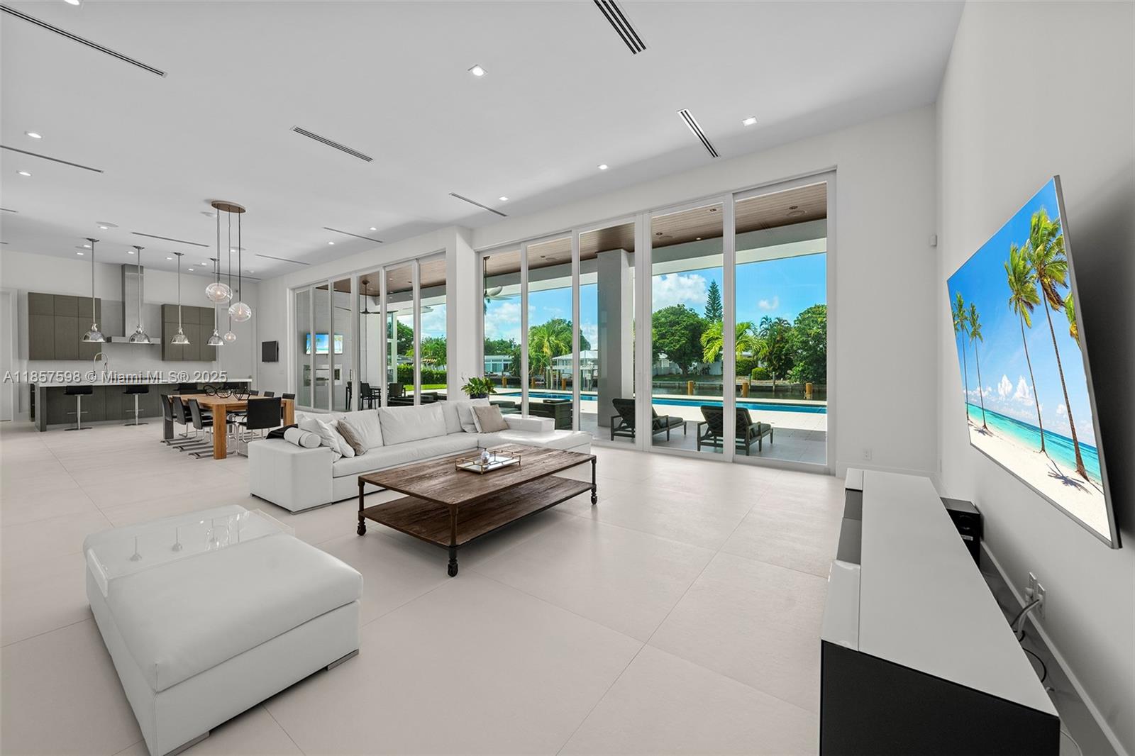 This Coral Ridge residence delivers clean lines, natural light, and a layout designed for impact. Floor-to-ceiling glass walls frame the living spaces, bringing the outdoors in and showcasing 100 feet of prime water frontage. The kitchen anchors the home with bold finishes and a seamless flow into expansive living and dining areas, all under soaring 13-foot ceilings.
Every room is curated with purpose, from the serene primary suite to the open entertaining spaces, with an easily convertible room ready to become an additional bedroom if desired. Outside, a private pool is surrounded by mature landscaping, creating a secluded retreat. Super clean and modern in design, this home sits in a quiet location near the water, offering presence without saying a word.