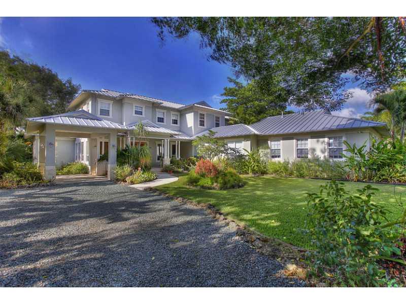 Leave ordinary behind in this custom Plantation style gated home. Located within walking distance to top schools. Stunning Brazilian teak floors and light filled spaces will capture your heart. Living Room with white washed vaulted wood ceilings. Magazine  quality well-appointed kitchen with family sized adjoining family room is the heart of the home. 50x20 saline pool with jetted swim lane. Tennis court. Outdoor gazebo. Wonderful gardens and porches. Impact glass, generator, 2 car garage and carport.