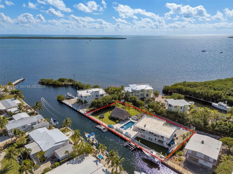 Nearly 200 feet of deep-water dockage with immediate ocean access makes this exceptional Florida Keys retreat a boater's dream. This solid concrete 3-bedroom, 2-bath home features a concrete roof, impact windows and doors, a wrap-around balcony, and a versatile lower-level studio space with a full bath--perfect for guests or extended living. Designed for effortless island living, the updated interior is move-in ready with fresh finishes throughout and a Viking gas stove anchoring the kitchen. Outdoors, a stunning 20' x 30' tiki hut overlooks a resort-style pool and hot tub, creating the ultimate space for entertaining or unwinding in true tropical fashion. The property includes two boat lifts (30,000-lb and 10,000-lb), accommodating multiple vessels with ease. Located on a private, gated street at MM 97 and just one lot from the oceanfront, this home offers rare privacy paired with unbeatable access. Additional features include ample parking, turf grass, paver walkways surrounding the pool and garage, and plenty of space for all your toys. The adjacent vacant lot with tiki hut is a separate folio and offers future build potential. Designed for family, friends, and the ultimate Florida Keys lifestyle.