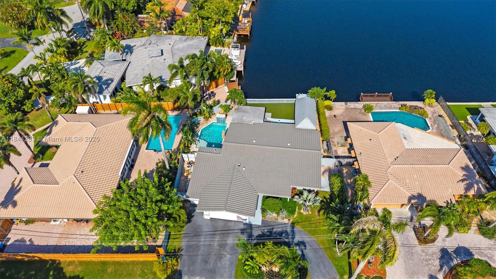 Waterfront Home with spectacular Lake views in desirable Coral Heights 3 bedroom 2 Bath Pool Home 2435 sq. ft. including 2 car garage. Fenced property, Heated Salt Water Pool with waterfall, gas pool heater, Dock, covered Tiki Hut with new hot tub with solar lights. Open dining and living room w/ built-ins overlooking the lake – kitchen w/gas stove, kitchen bar counter, Stainless Steel appliances, Spacious Primary Bedroom with sitting room with water views, large closets, 2 more bedrooms, impact windows, gas water heater, laundry room w washer/dryer, lots of cabinets, tile and wood flooring throughout, 2 car garage with tile floors, workshop, driveway, and Barrel tile roof. Near Shopping, Beach, Transportation and Airport.