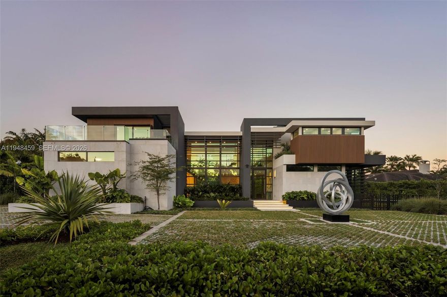 Tucked away on a quiet Pinecrest cul-de-sac, this newly completed two-story estate delivers refined modern luxury with exceptional privacy and architectural presence. Offering 7 bedrooms and 7.5 baths, the residence is thoughtfully designed with curated European finishes throughout, including warm wood tones, natural stone, and bespoke marble imported from Italy and Spain. Expansive walls of architectural glass flood the interiors with natural light while creating a seamless connection between indoor and outdoor living spaces.
The chef’s kitchen is both striking and functional, featuring premium appliances, custom millwork, generous prep space, and a temperature-controlled wine display, all opening effortlessly to the main living and dining areas—ideal for entertaining at scale or intimate gatherings. Elevator access serves both levels for added convenience.
The primary suite is a true private retreat, complete with a sitting lounge, serene views, and a spa-inspired bath featuring a skylight, soaking tub, dual vanities, and refined stone finishes. Additional bedrooms are well-appointed and thoughtfully positioned for comfort and privacy.
Resort-style grounds complete the offering, showcasing an infinity-edge pool, guest house, and lush, tranquil landscaping that enhances the sense of seclusion. A rare opportunity to own a newly built, design-forward residence in one of Pinecrest’s most desirable settings.