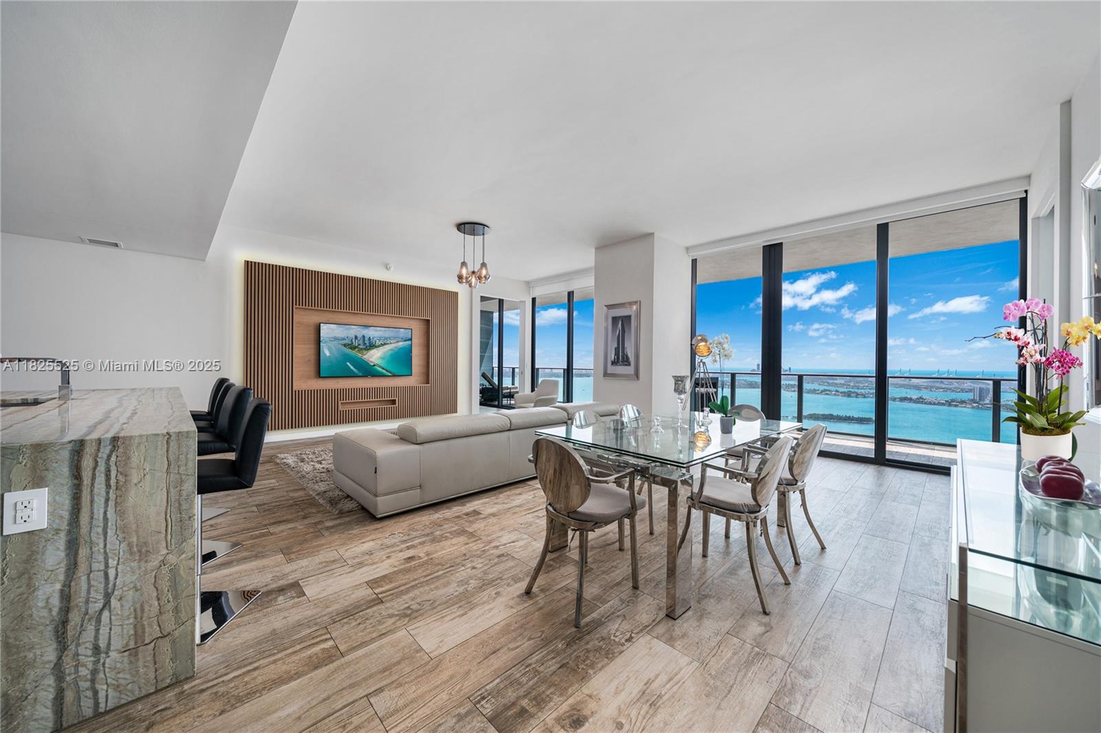 Stunning fully furnished penthouse on the 50th floor of Paraiso Bay with breathtaking bay, ocean, and skyline views. Enjoy soaring 10-ft ceilings (exclusive to penthouse level) and ultimate privacy with only 4 units per floor. This elegant 4BD/4,5B features porcelain floors, floor-to-ceiling windows, and a spacious layout. Recently upgraded with a custom wood-paneled wall and recessed lighting, adding warmth to the living area. Motorized shades in the two main bedrooms and a Nest smart A/C system. Oversized 420 SqFt terrace ideal for entertaining. Resort-style amenities: pool, spa, gym, theater, bowling, tennis, sauna, steam room, and more. Prime Edgewater location, minutes to Wynwood, Design District, and Brickell. Easy to show.