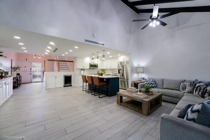 Beautifully updated golf course townhome in Pembroke Pines with LOW HOA FEES! This move-in ready home features soaring high beam ceilings, porcelain wood-look tile, and a stylish living area with a modern faux fireplace. The open-concept kitchen is designed for entertaining, offering quartz countertops, stainless steel appliances, and a large island with a custom bar and wine fridge. Custom built-in closets with sliding barn doors add both function and designer charm. Relax and unwind on the screened-in patio overlooking the golf course—perfect for enjoying peaceful views and outdoor living. Major updates include a new roof (2023) and new A/C (2024). The community has also been recently refreshed with modern exterior paint colors. Enjoy resort-style amenities including a pool, pickleball, tennis, and basketball courts. Includes 2 assigned parking spaces. Conveniently located near shopping, dining, and parks.