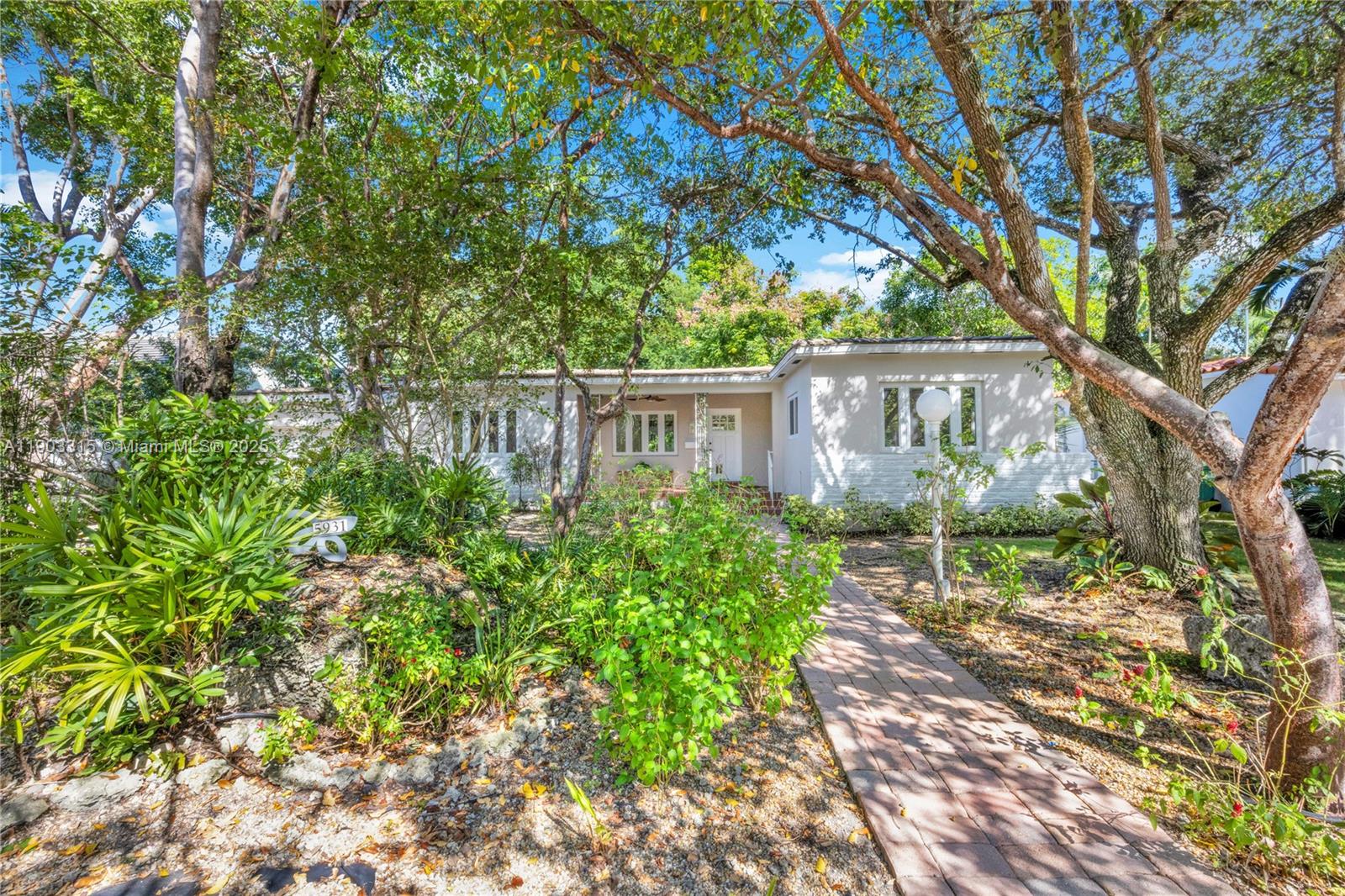Welcome to this charming 3-bedroom, 2-bathroom Biltmore Heights home with hardwood floors throughout living areas and bedrooms. The spacious sun-drenched family room features wall-to-wall windows, open beam ceiling and tile flooring, while the inviting front porch offers beautiful Southern exposure surrounded by mature shade trees. Inside, discover an updated kitchen w/skylight and formal dining room. Authentic 1950s vintage touches include original bathroom tiles and classic Dade County pine wainscoting in one bedroom. Impact windows and doors provide hurricane protection and quiet. The converted garage offers versatile workspace and laundry area, perfect for home office or studio (the SF of the converted garage is NOT included in the living area total). One of Miami's best neighborhoods!