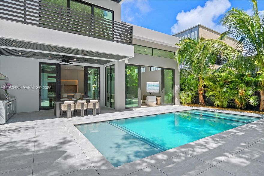 A striking modern residence in Buena Vista, defined by soaring ceilings, dramatic scale, and a seamless blend of design and functionality. Expansive floor-to-ceiling glass floods the interiors with natural light, while wide-plank oak flooring and curated lighting details create a warm, elevated atmosphere throughout. The open-concept living spaces are designed to impress, flowing effortlessly into generous outdoor areas and private balconies. At the center of the home, the kitchen features sleek custom cabinetry, natural stone surfaces, and integrated accent lighting, complemented by high-end appliances and built for both everyday living and entertaining. This 5-bedroom, 6-bath home offers oversized en-suite bedrooms with custom closets, along with a two-car garage for added convenience. Smart home integration, a full Sonos sound system, and a comprehensive security setup provide comfort, control, and peace of mind. The backyard is a private retreat with a heated saltwater pool and summer kitchen, perfect for indoor-outdoor living. A detached guest house doubles as a wellness space, complete with its own living area, kitchen, sauna, cold plunge, and full bath. Ideally positioned just minutes from the Design District, Downtown Miami, and Miami Beach.