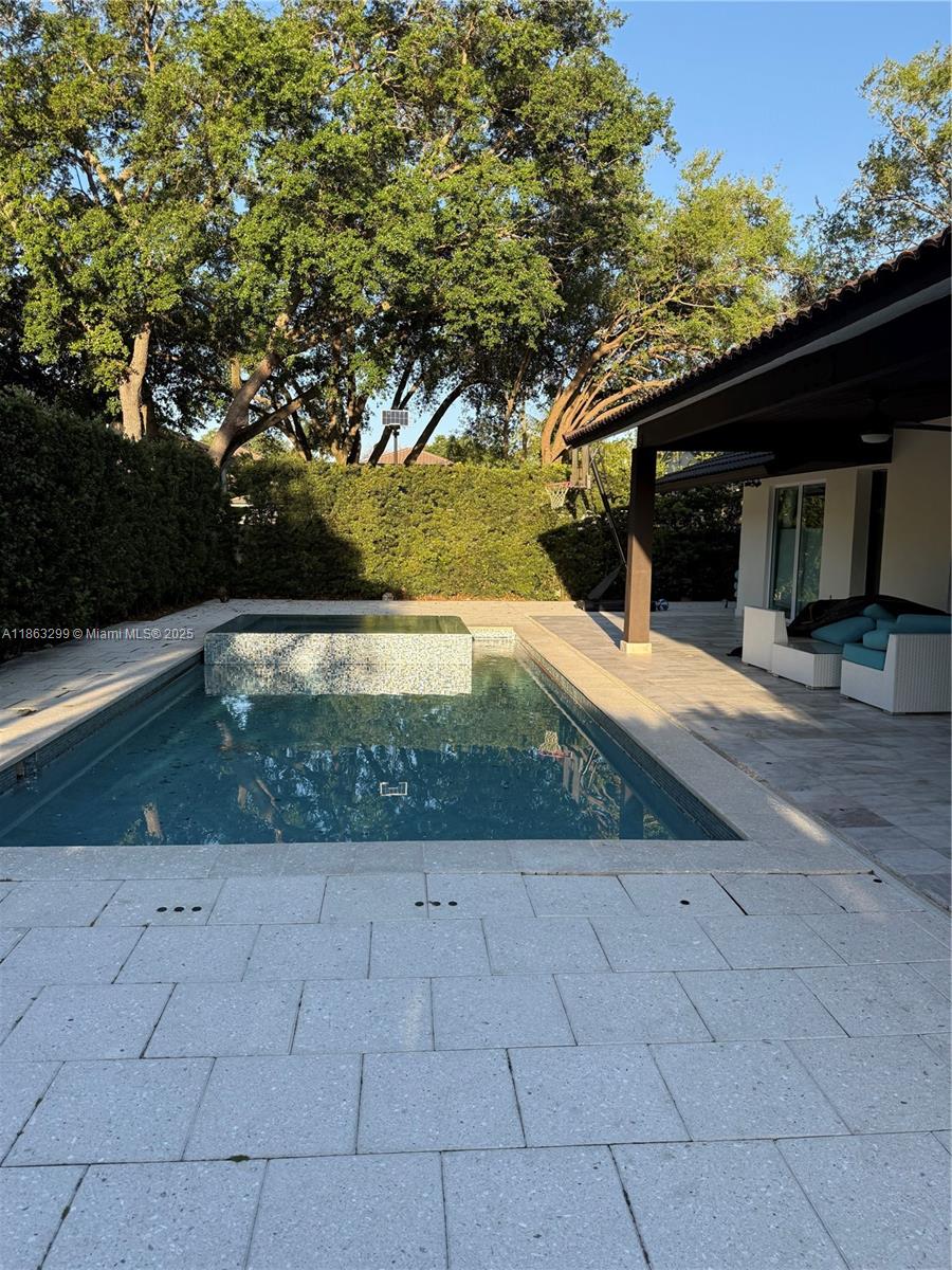 Elegant and modern residence featuring a bright open floor plan with marble flooring throughout. Gourmet kitchen with sleek European-style cabinetry, double ovens, and quartz countertops, complemented by statement crystal chandeliers. Spacious dining and living areas with floor-to-ceiling windows overlooking the pool. Luxurious bathrooms with dual vanities, marble finishes, and frameless glass showers. Enjoy a private backyard retreat with a sparkling pool, spa-style waterfall feature, and covered patio perfect for entertaining. A true move-in ready home with timeless sophistication and resort-style living