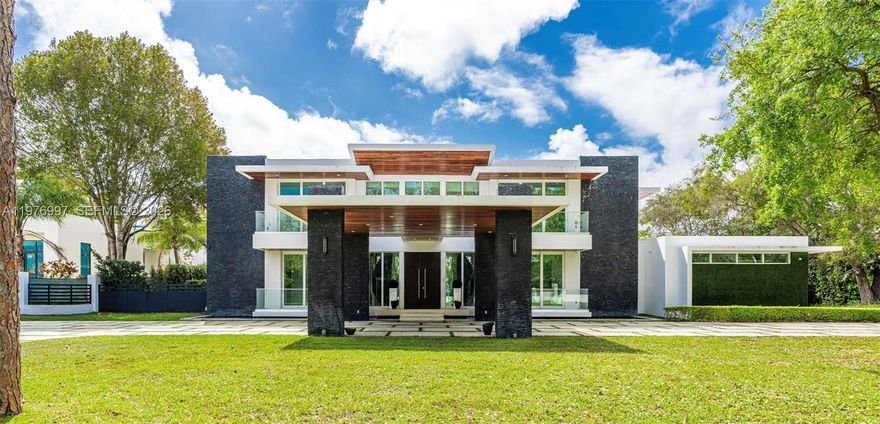 La Premiere Realty is pleased to introduce this extraordinary 2020 contemporary estate in Pinecrest, where architectural brilliance and refined luxury meet behind private gates. Spanning 10,122 sqft of adjusted living area, the residence showcases a striking modern façade with clean lines, natural stone accents, and a dramatic covered entrance that sets the tone for the elegance within.
A breathtaking double height grand foyer welcomes you with a cascading crystal chandelier and an elegant dual floating staircase with glass railings and marble steps, creating a stunning centerpiece. Floor-to-ceiling windows fill the home with natural light while seamlessly connecting the interior spaces with the lush tropical surroundings.
This exceptional residence features 8 bedroom, 10/1 bathroom, a private elevator, and a 3-car garage, all finished with impeccable craftsmanship and high-end materials. At the heart of the home lies a gourmet chef’s kitchen equipped with premium Wolf appliances, custom cabinetry, and generous preparation space, perfect for entertaining.
The primary suite offers tranquil views of the resort style backyard, two expansive walk-in closets, and a spa-inspired marble bathroom with a soaking tub and oversized glass shower.
The estate includes a complete security system and integrated speakers throughout the home.Enjoy a stunning infinity edge pool, sunken lounge, and covered summer kitchen surrounded by mature palms, creating a private resort-style setting.