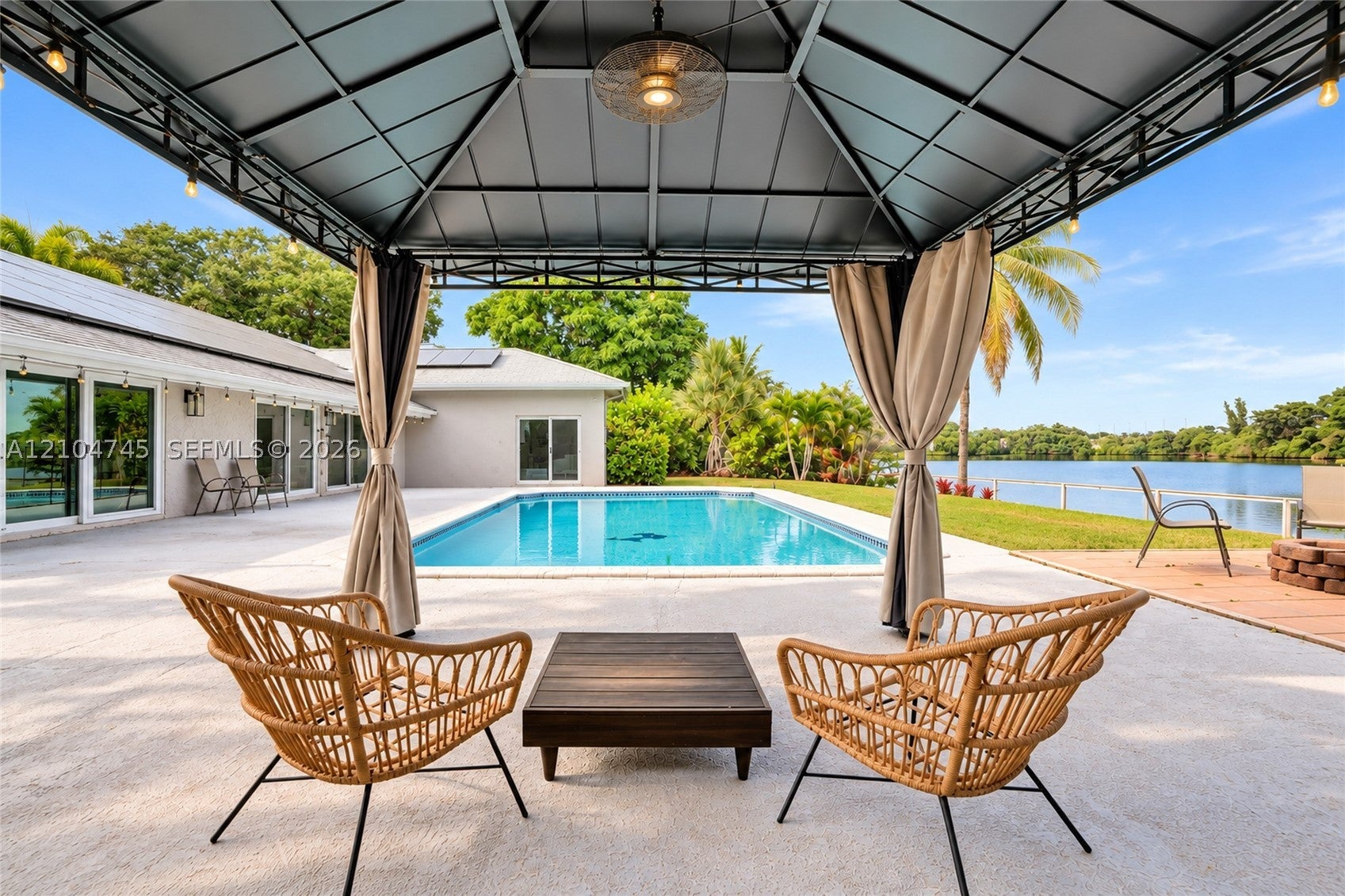 Covered cabana seating beside the heated pool at 1020 Bayberry Point Dr, with the lake beyond