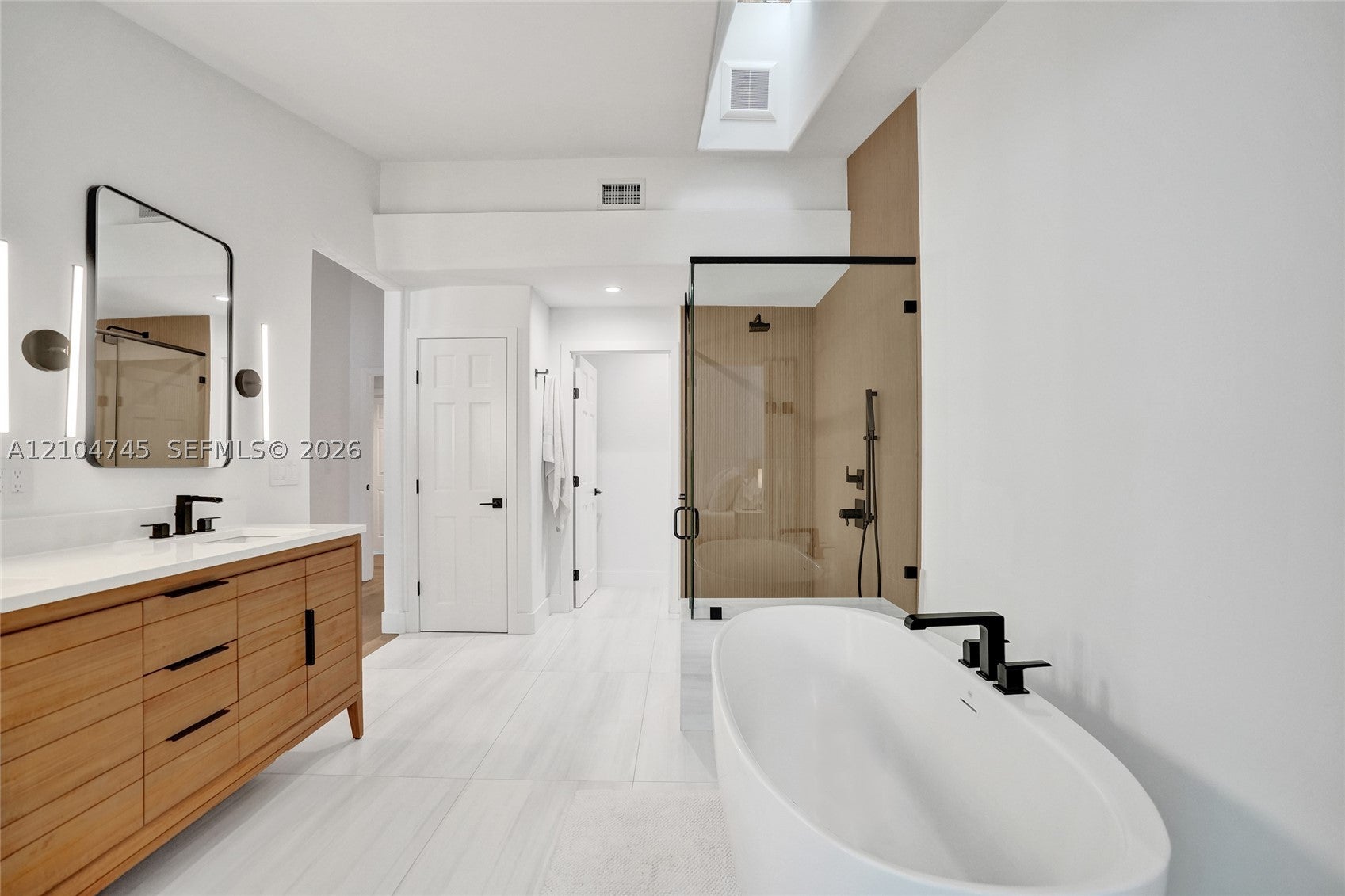 Remodeled bathroom with a wood vanity, freestanding tub and glass shower