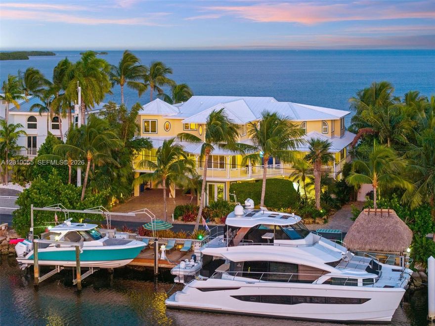 Where the ocean meets elegance, 545 Ocean Cay delivers an extraordinary expression of Keys coastal living. Set within the coveted, gated enclave of Ocean Cay Estates, this oceanfront residence is crafted for those who value refined comfort, effortless entertaining, and world-class boating. A private tropical oasis unfolds along the water's edge, anchored by an award-winning resort-style pool featuring five waterfalls, a walk-over bridge, a swim-up table, and a separate infinity spa overlooking the blue horizon. The outdoor living spaces feel like a retreat of their own—sun terraces, shaded lounging, lush landscaping, and uninterrupted ocean breezes. Two fully equipped outdoor grill/kitchen areas allow for seamless entertaining, from casual afternoons by the pool to unforgettable sunset dinners. For boaters, this is the ultimate base. Enjoy 100 ft of deep-water dockage with premium Zuri decking, multiple dock boxes, a shaded Tiki, dedicated lounging area, boat lift, and a specialty-designed kayak elevator for easy launching. Inside, the home blends soaring ceilings, natural light, and thoughtful craftsmanship. The chef's kitchen impresses with a Miele gas stove, oversized Sub-Zero refrigeration, stone countertops with integrated backlighting, and seamless flow to the dining and great rooms. A second bar area creates the perfect spot for conversation and cocktails. A private elevator services all three levels.