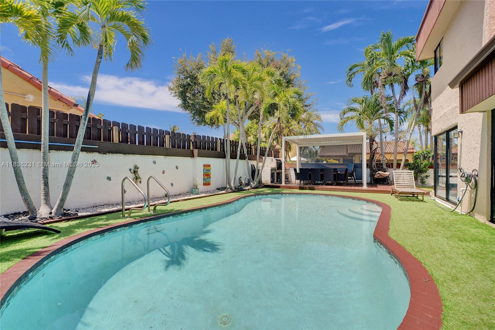 This stunning 4-bedroom, 3-bath home in California Club Homes, Miami, combines modern elegance with comfort. The backyard is an entertainer's dream, featuring a sparkling pool, lush landscaping, a shaded dining area, and a custom-built barbecue station. Inside, the bright, airy layout boasts high ceilings, stylish living spaces, and a gourmet kitchen with sleek cabinetry, stainless steel appliances, and a spacious island. The serene bedrooms include a luxurious master suite with a spa-like ensuite. A flex room adds versatility, while the two-car garage and convenient laundry room enhance functionality. Located near parks, shopping, dining, and top-rated schools, this home offers the perfect blend of luxury and convenience.