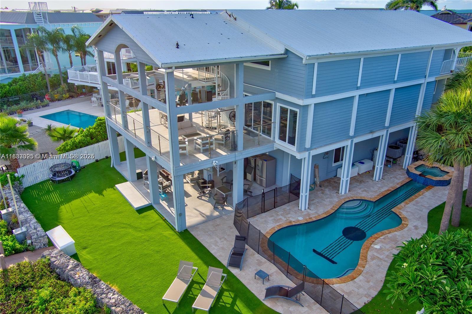 Paradise awaits in this elegant bayfront home in Buccaneer Point. With 4 beds, 4 baths, and wraparound verandas offering panoramic bay views, this residence blends coastal charm with modern comfort. Enjoy a private dock with boat lift, sandy beach access, and a chef's kitchen with granite counters and stainless appliances. The third-floor primary suite features a private balcony and spa-style tub, all accessible by elevator. Complete with a spacious garage and storage for all your water toys- this is true Keys living at its finest