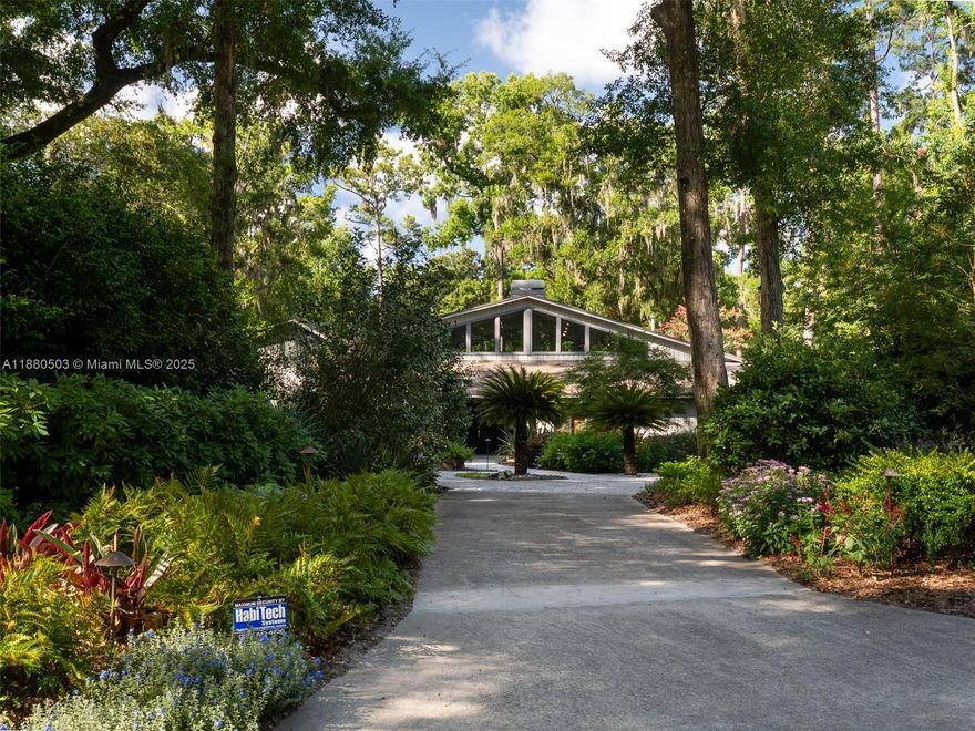 Elegant Retreat on Over an Acre Near the University of Florida Privately set in the sought-after Hermitage neighborhood, this  home rests on 1.1 landscaped acres. Updated with design-forward style, the interior features travertine floors, soaring ceilings, walls of glass, and a dramatic fireplace. Living and entertaining zones include a custom backlit quartzite bar, chef’s kitchen with dual prep stations, waterfall island, induction cooktop, steam/convection ovens, and sleek cabinetry—overlooking resort-style pool. The primary suite offers a soaking tub and oversized shower A secondary wing hosts two bedrooms, shared bath, gym, and media room. With smart home integration, studio cottage, and outdoor oasis, this retreat blends modern luxury with timeless appeal.