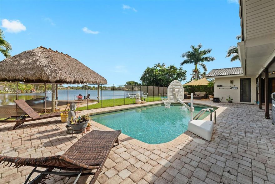 Lakefront pool home with a true resort-style backyard! Enjoy expansive paver patio space with multiple outdoor living areas including a gazebo/tiki-style lounge, firepit, private jacuzzi, and your own fishing dock with tranquil water views—ideal for relaxing or entertaining. The pool and patio create the perfect setting for sunsets and weekend gatherings. Inside, the home offers bright open living and dining areas with warm flooring, great natural light, and seamless indoor/outdoor flow. The kitchen features wood cabinetry, gas cooktop, and stainless hood. Bathrooms include modern finishes with glass shower and dual vessel sinks. Rent includes landscaping and pool maintenance. Tenants qualify for discounted membership at Bonaventure Racquet Club with extensive amenities. Available now—schedule your private showing today.